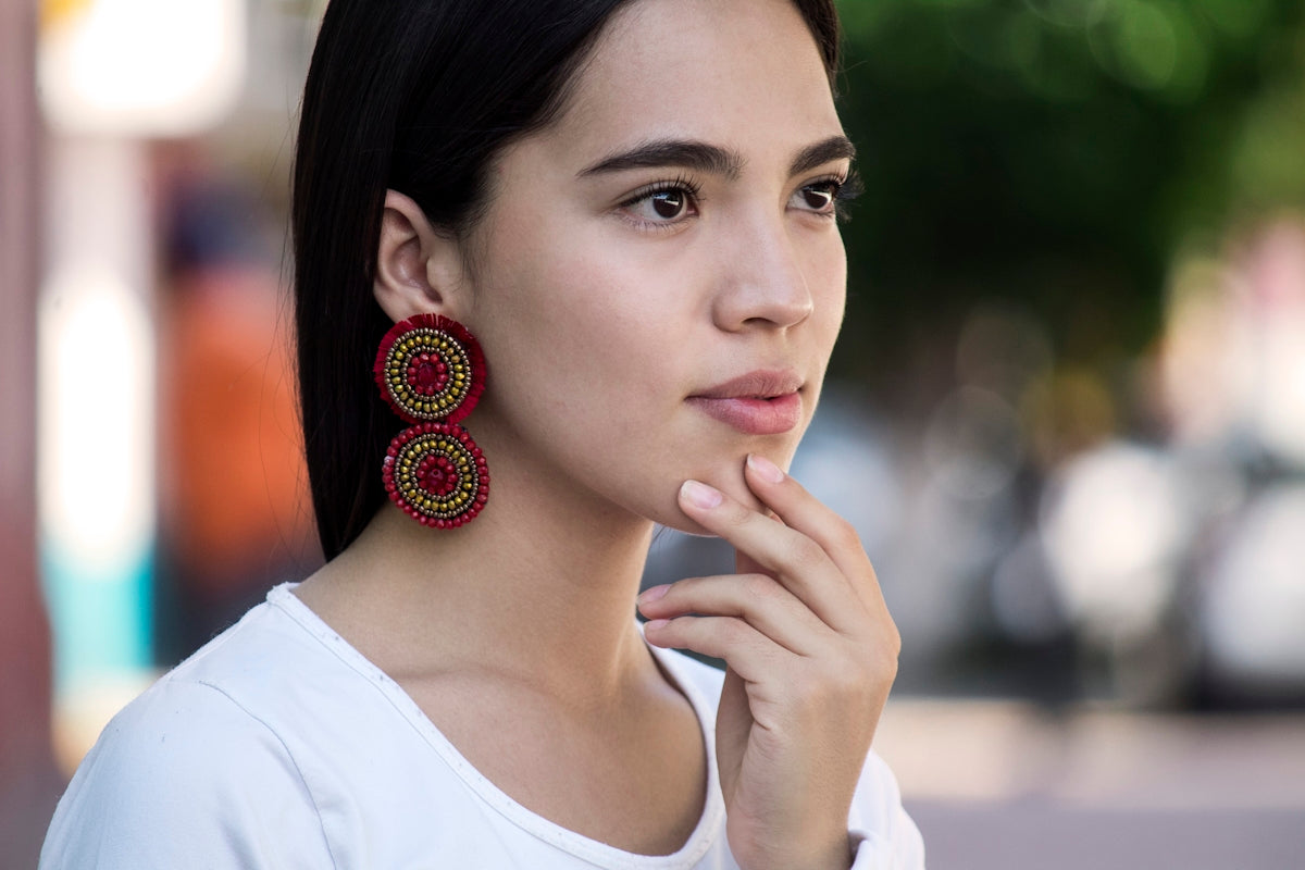 woman in white crew neck shirt wearing red and gold earrings