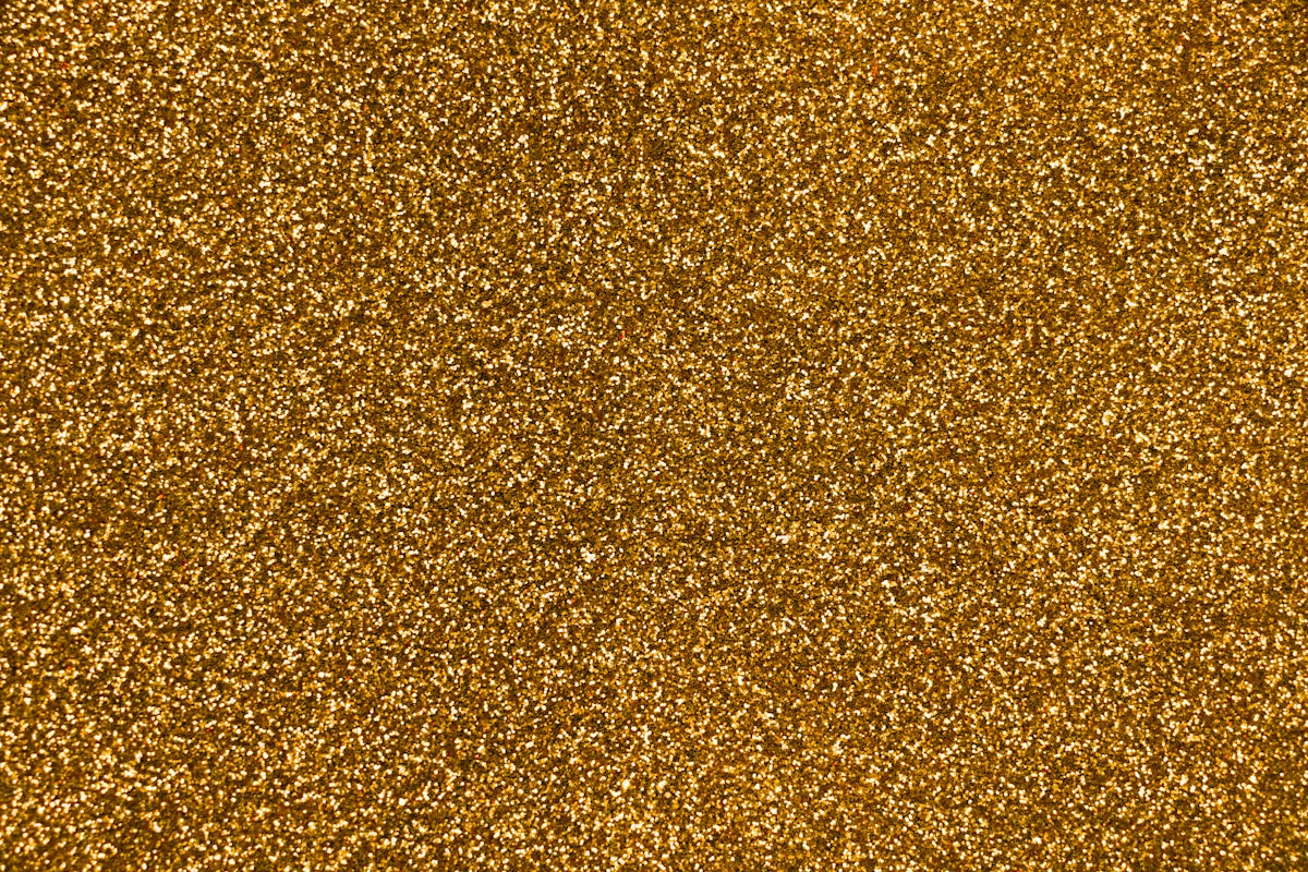 Close-up della textura scintillante per glitter d'oro, ideale per progetti creativi e design di gioielli.