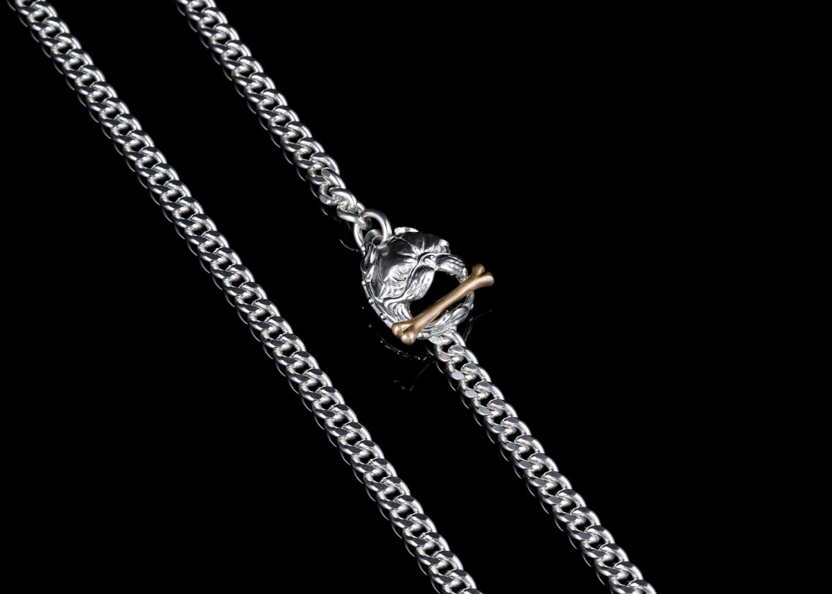 a silver chain with a gold clasp on a black background