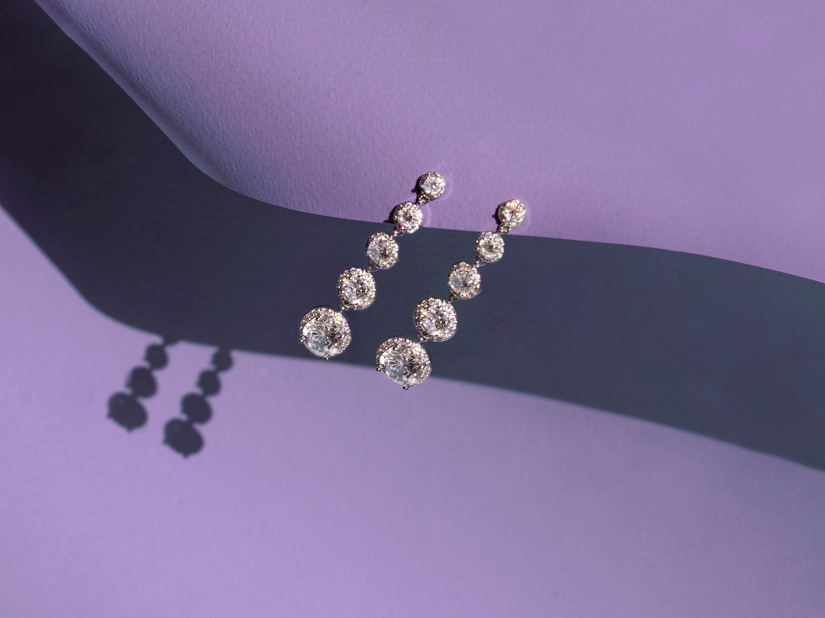 a pair of diamond earrings on a purple background