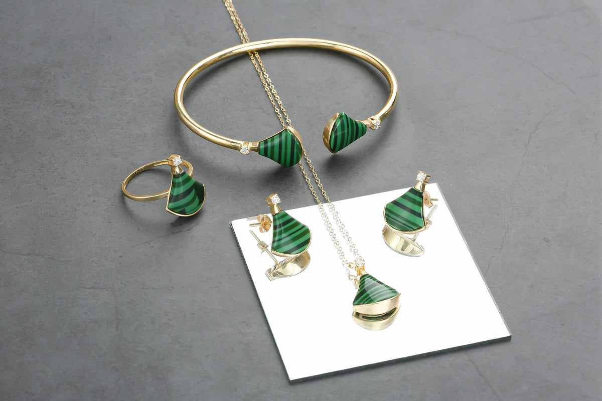 A set of green and gold jewelry on a gray surface
