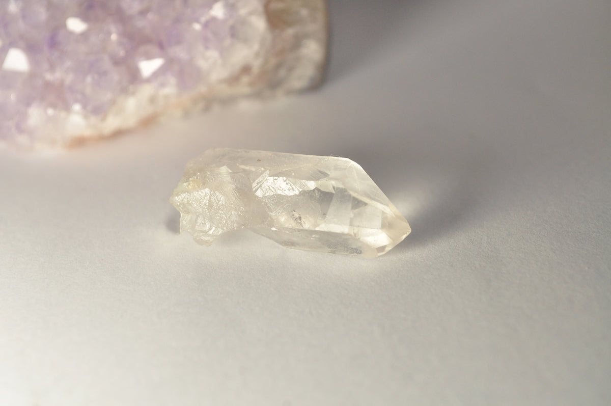 A clear crystal with purple quartz in the background.