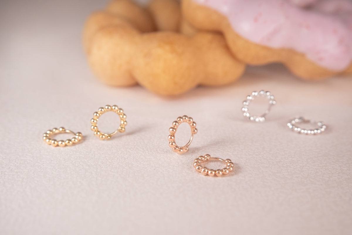 Earrings are displayed with a donut in the background.