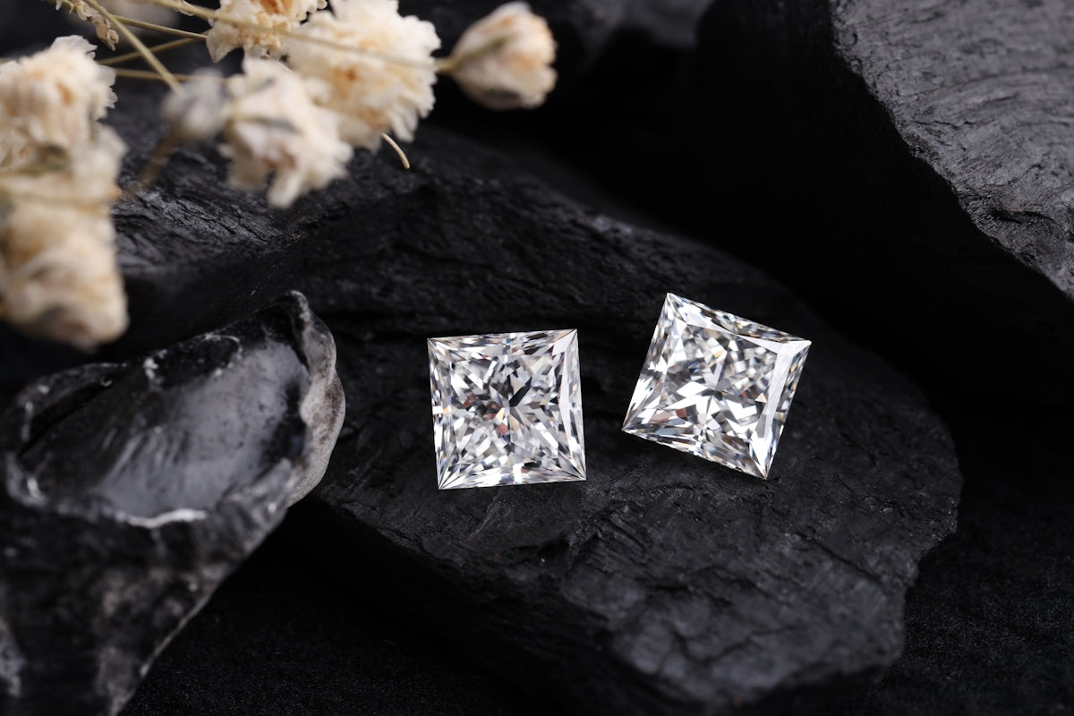 Diamond earrings rest on black rock.