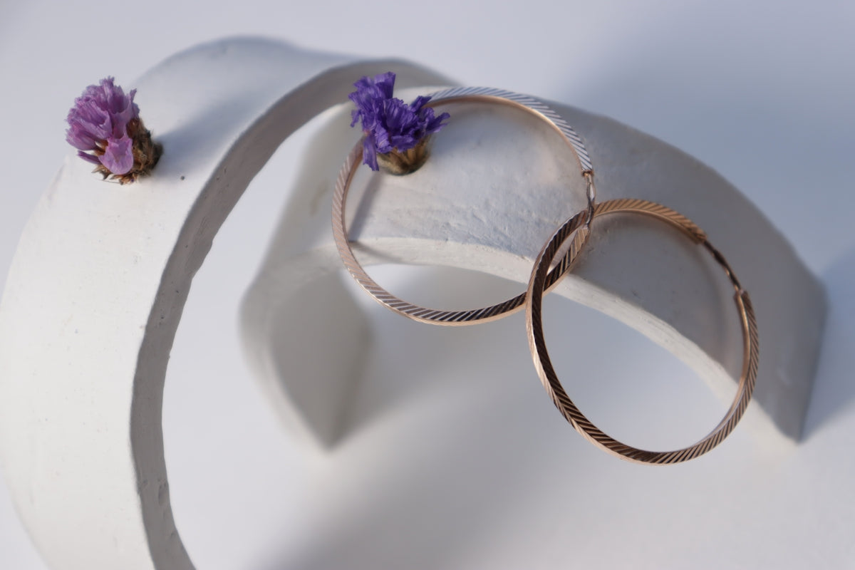 Hoop earrings and flowers on a white sculpture.