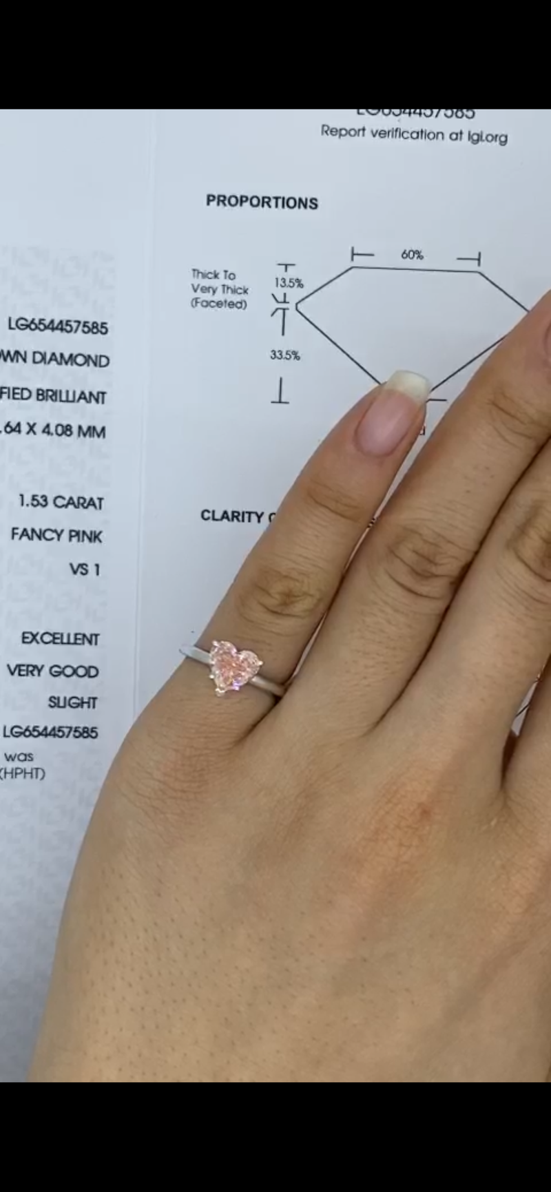 Hand wearing a delicate pink heart-shaped diamond ring, alongside a detailed report sheet.