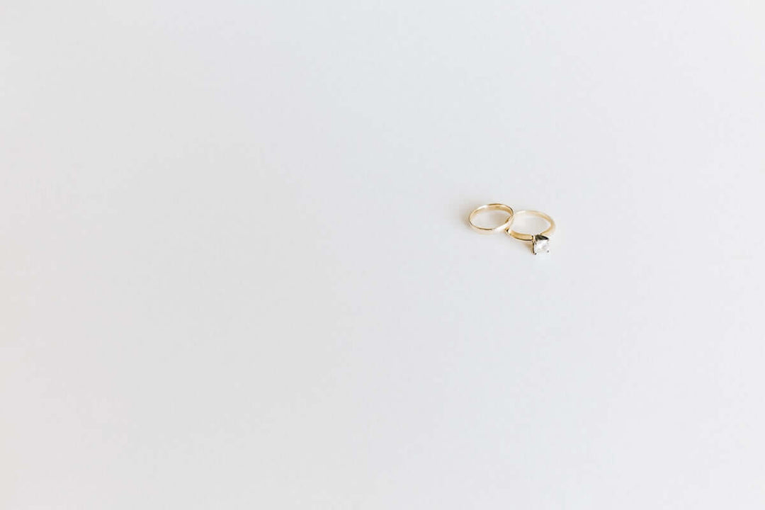 Elegante gouden ring met een diamant op een lichte achtergrond, met verfijnde vaartuigen van sieraden.