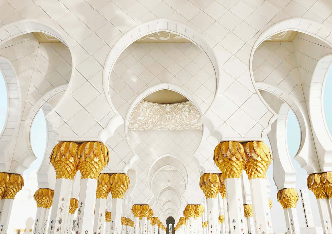 Interieuraanzicht van een grote architecturale ruimte met sierlijke bogen en gouden pilaren.