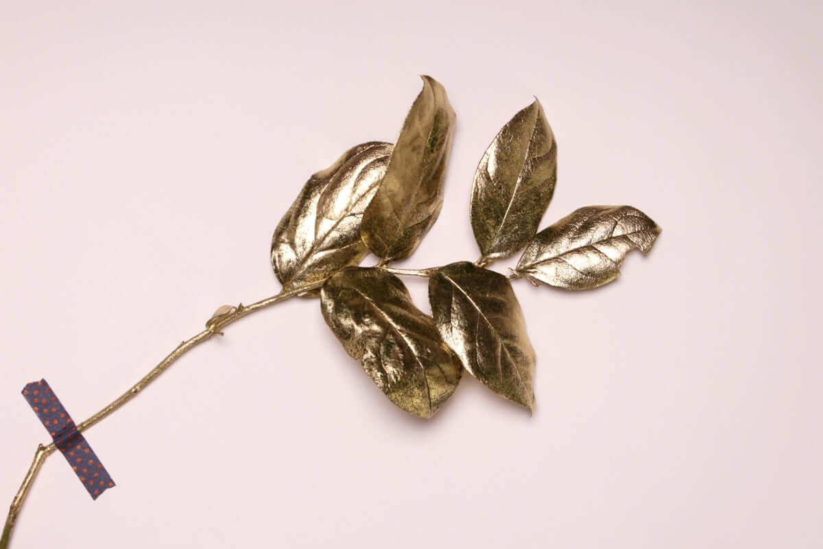 Golden metallic leaves on a branch, showcasing luxury and elegance in decorative art.