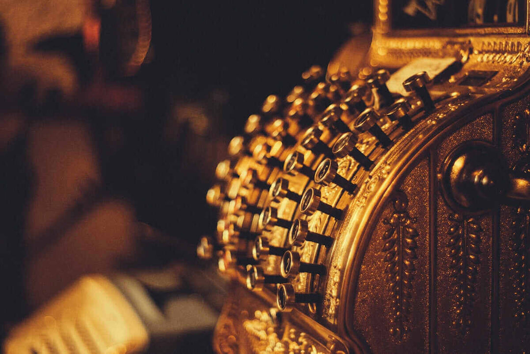 Close-up van een vintage gouden kassa met ingewikkelde details en sleutels.