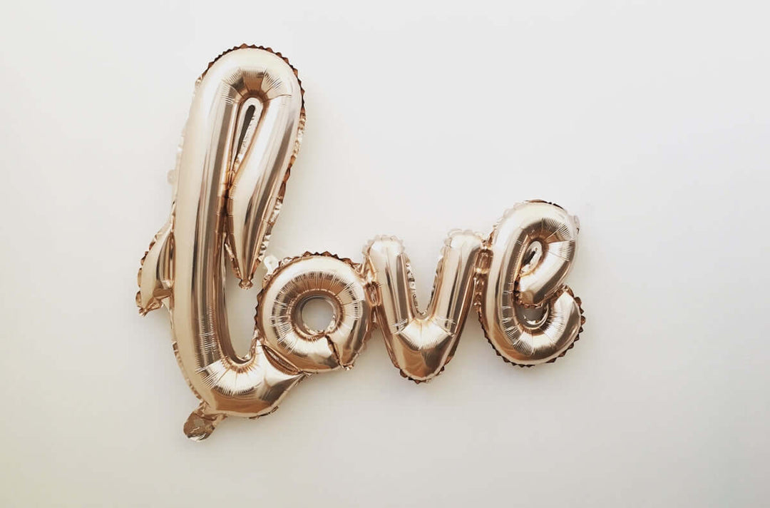 Rose Gold Love Ballon Decor tegen een witte achtergrond voor romantische feesten.
