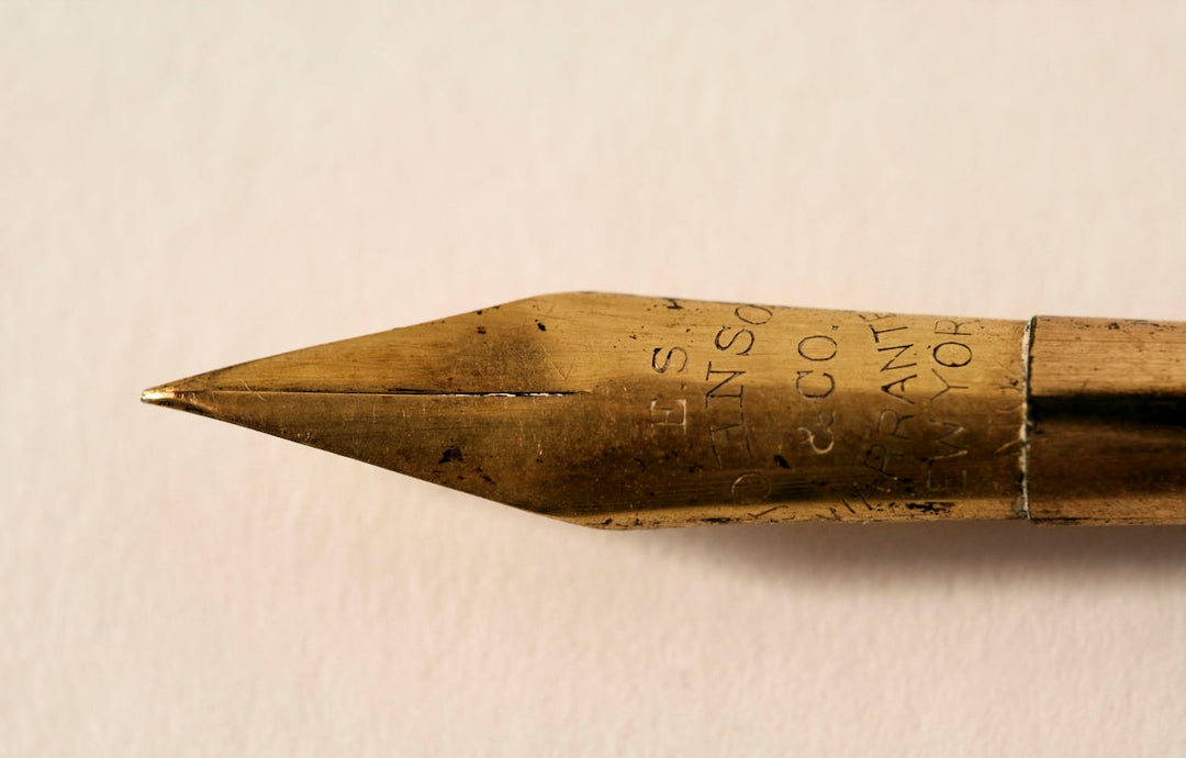 Close-up van een vintage messing fontein pen pen met ingewikkelde gravures en een puntige punt.