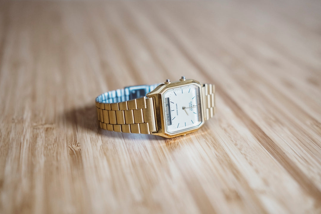 quadratische goldene analoge Uhr auf braunem Holzbrett