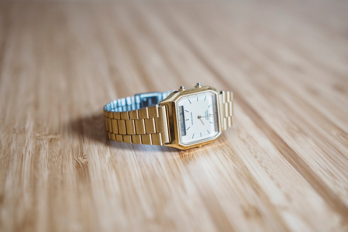orologio analogico di colore oro quadrato su bordo di legno marrone