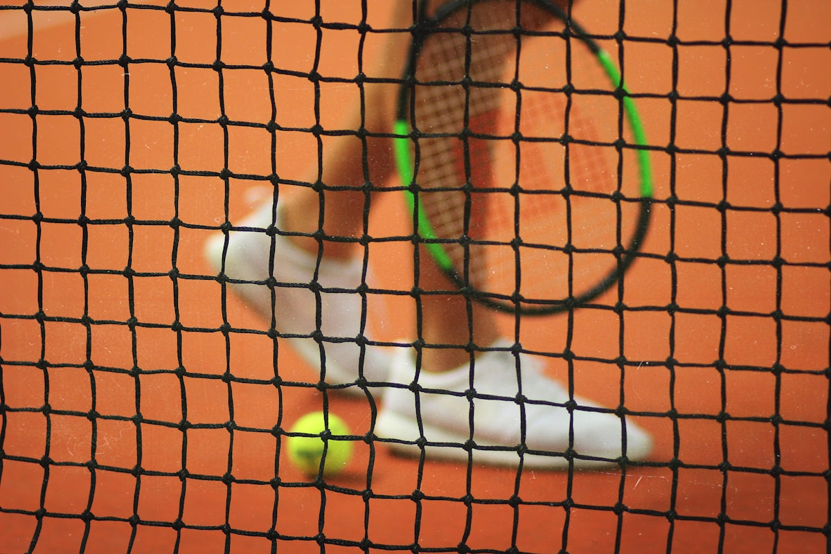 persona che indossa un paio di scarpe da ginnastica bianche basse mentre tiene la racchetta da tennis Wilson