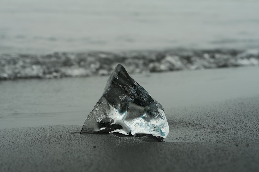 Fotografia in scala di grigi di Glass Shard by the Sea