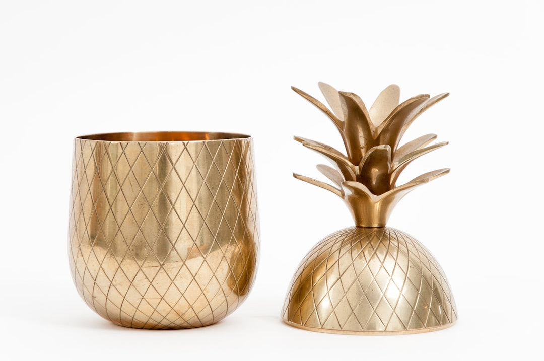 Elegante gouden ananan-vormige decor en bijpassende schaal op een witte achtergrond.