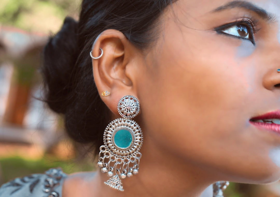 woman wearing silver and blue gemstone stud earring
