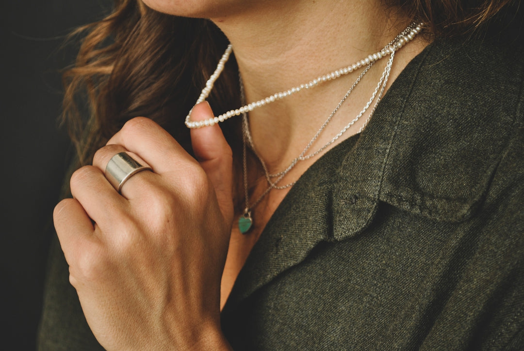 Donna in cappotto verde che indossa una collana d'argento