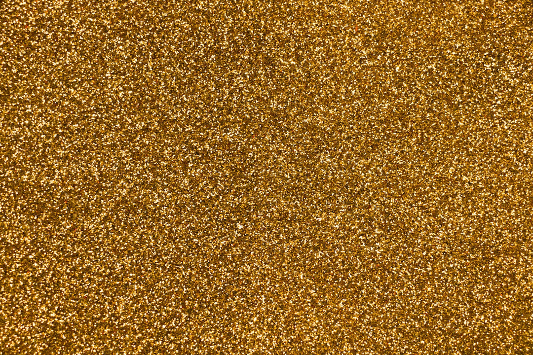 Close-up van sprankelende gouden glittertextuur, ideaal voor creatieve projecten en sieradenontwerp.