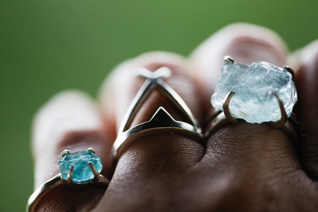 a person's hand holding two rings with blue stones