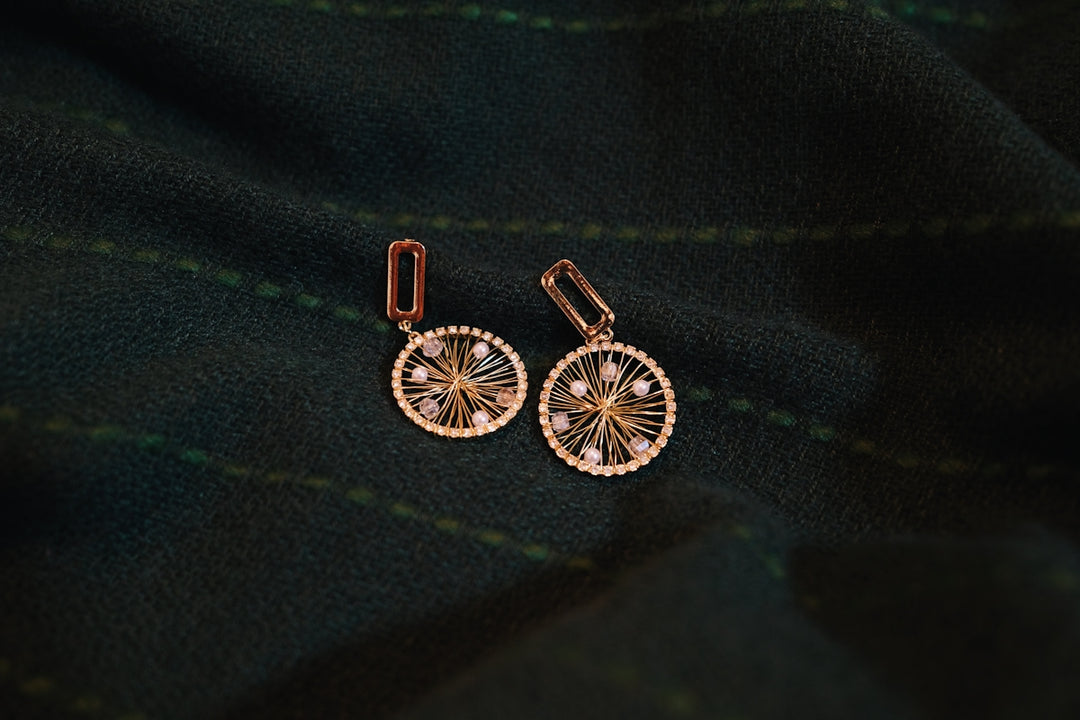 a pair of earrings sitting on top of a green cloth