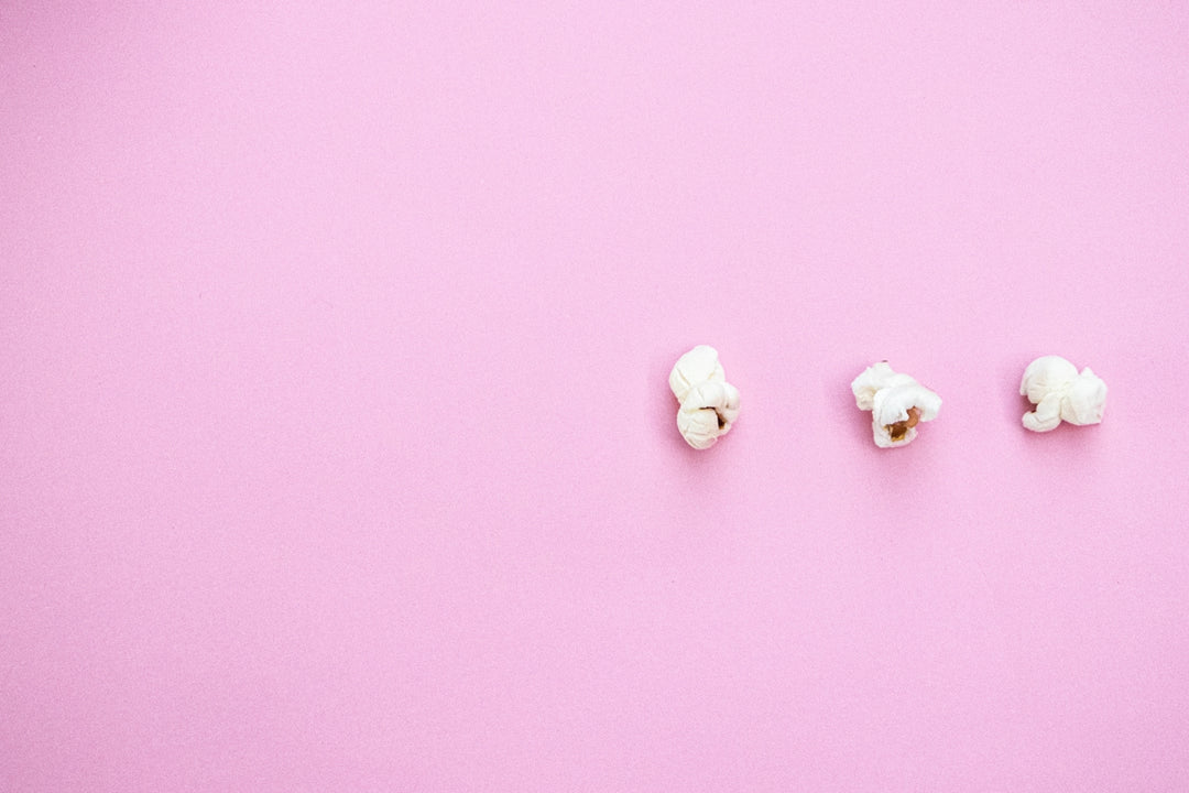 three pieces of popcorn on a pink background