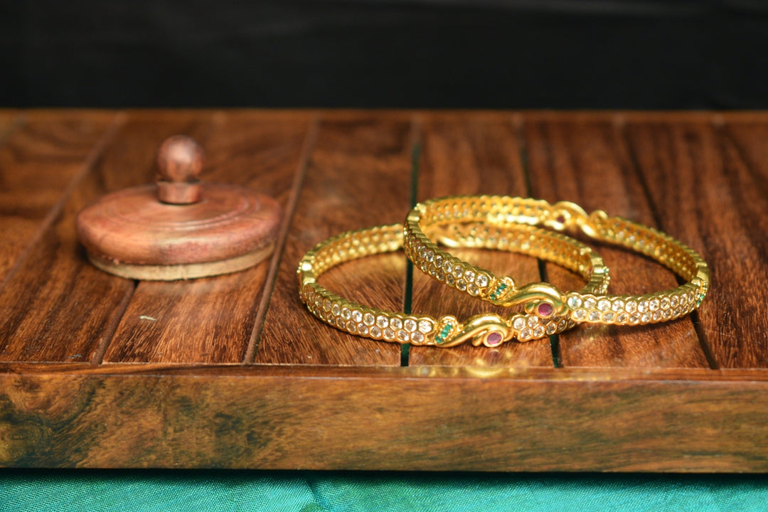 a couple of gold bracelets sitting on top of a wooden table