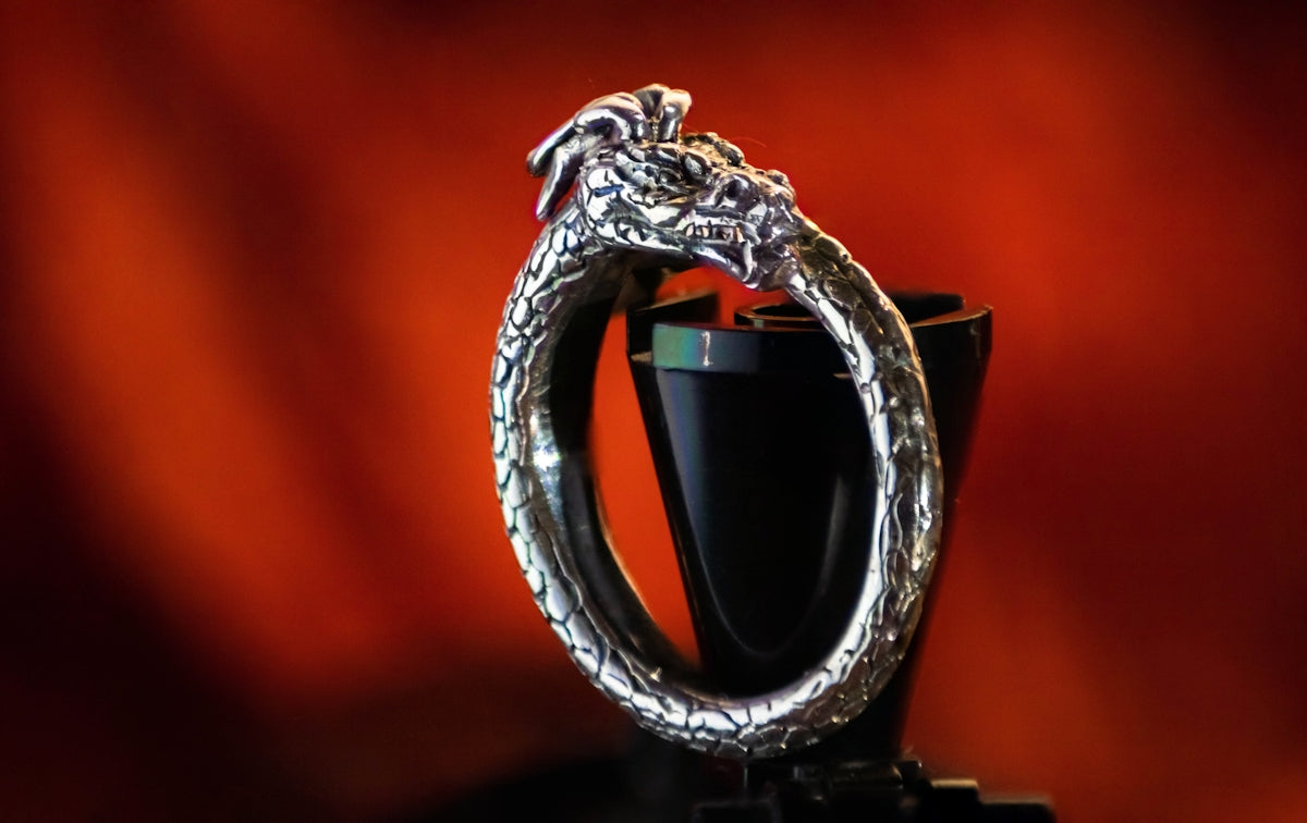 Un anello di drago d'argento seduto in cima a una tazza nera