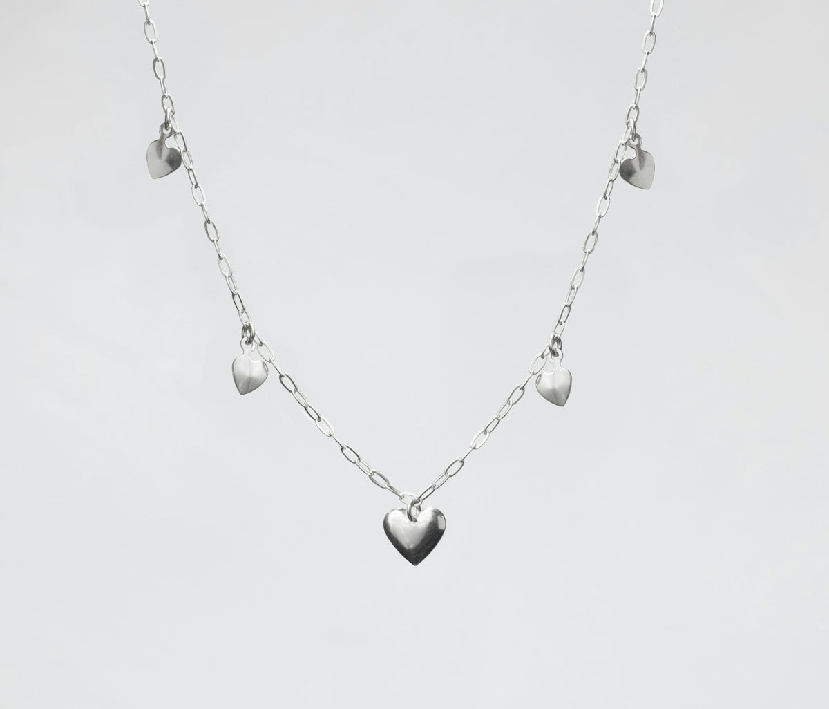a silver heart necklace on a white background