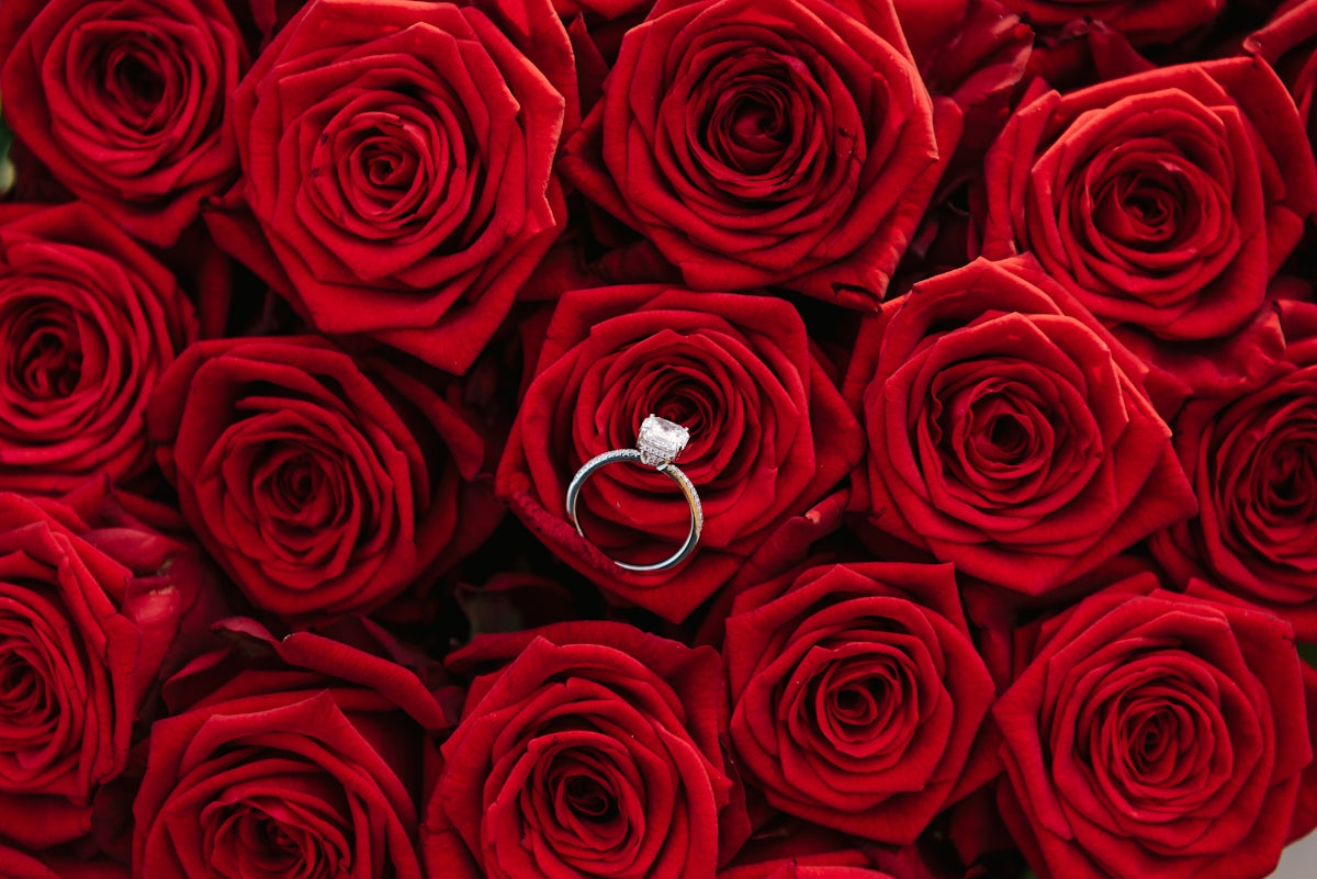 a bouquet of red roses with a wedding ring