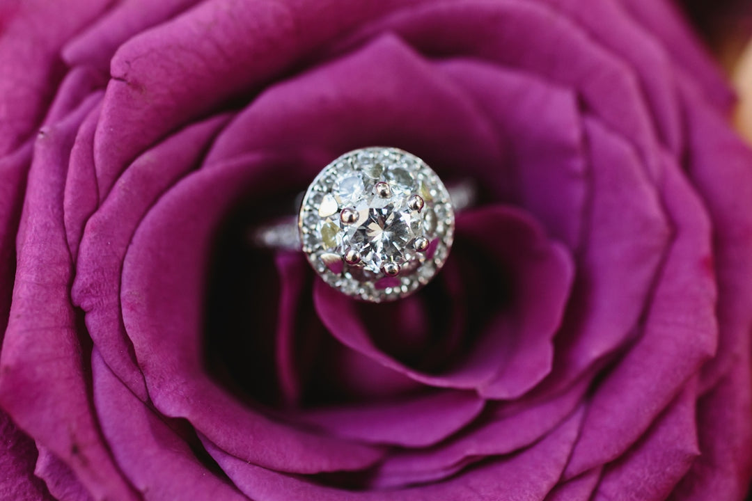 A close up of a rose with a diamond ring on it