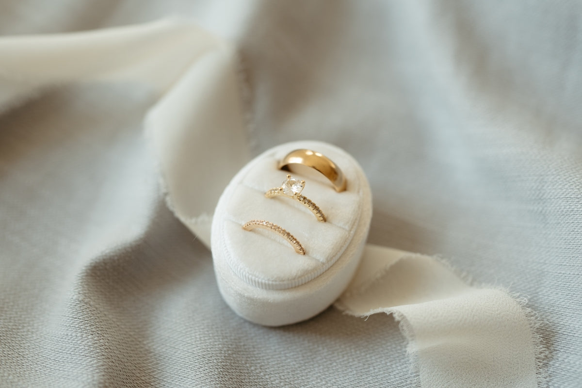A white ring box with a gold wedding band