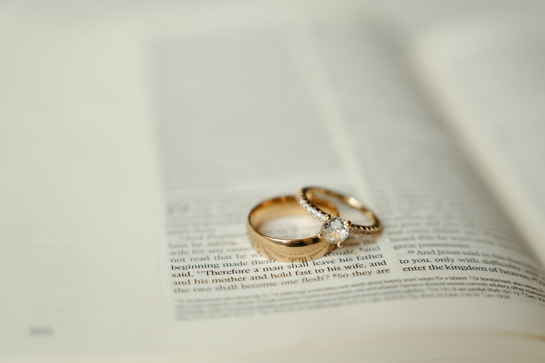 Two gold wedding rings sitting on top of an open book