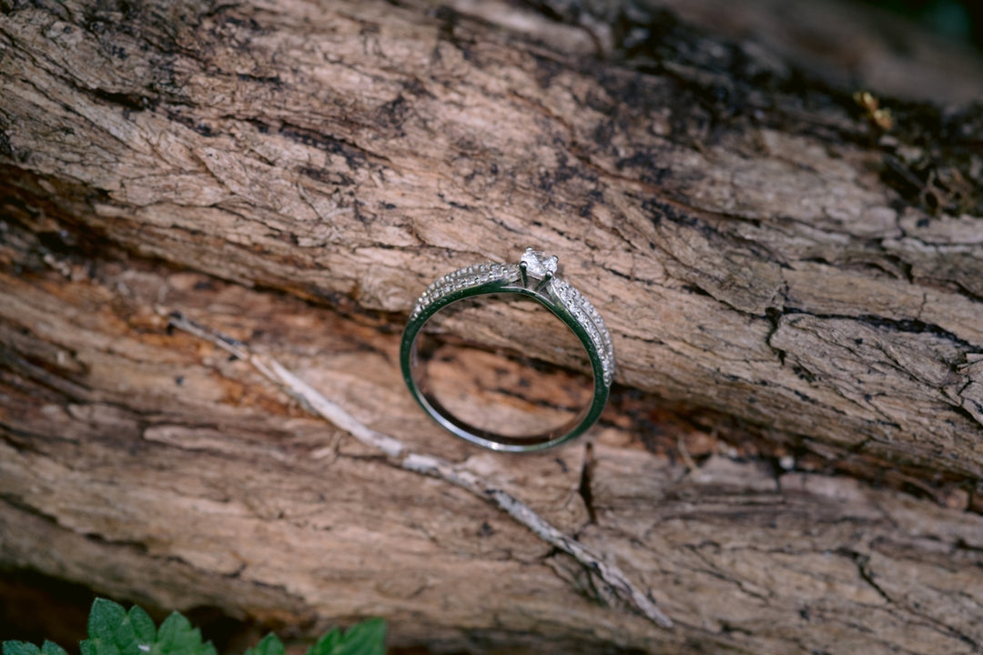 A diamond ring rests on a piece of wood.