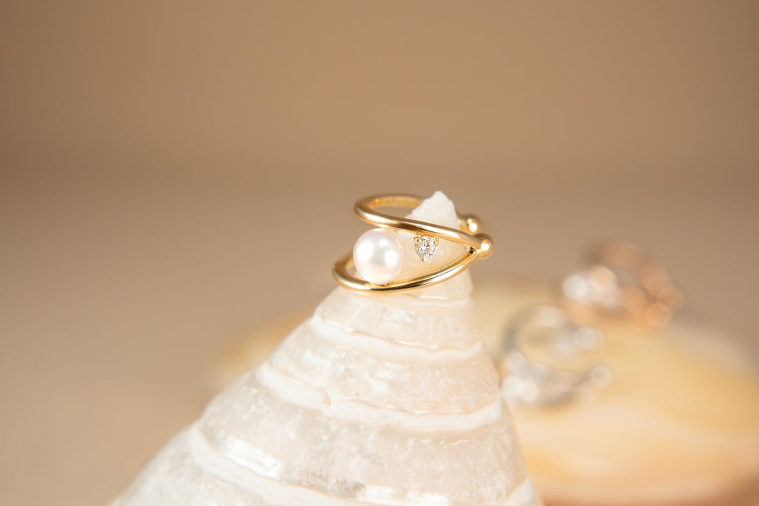 A golden ring encircles a pearl on a shell.