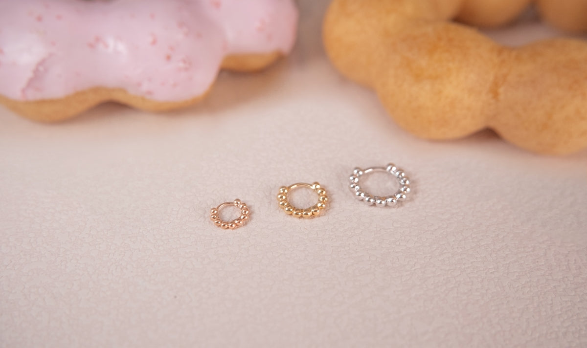 Three earrings sit next to doughnuts.