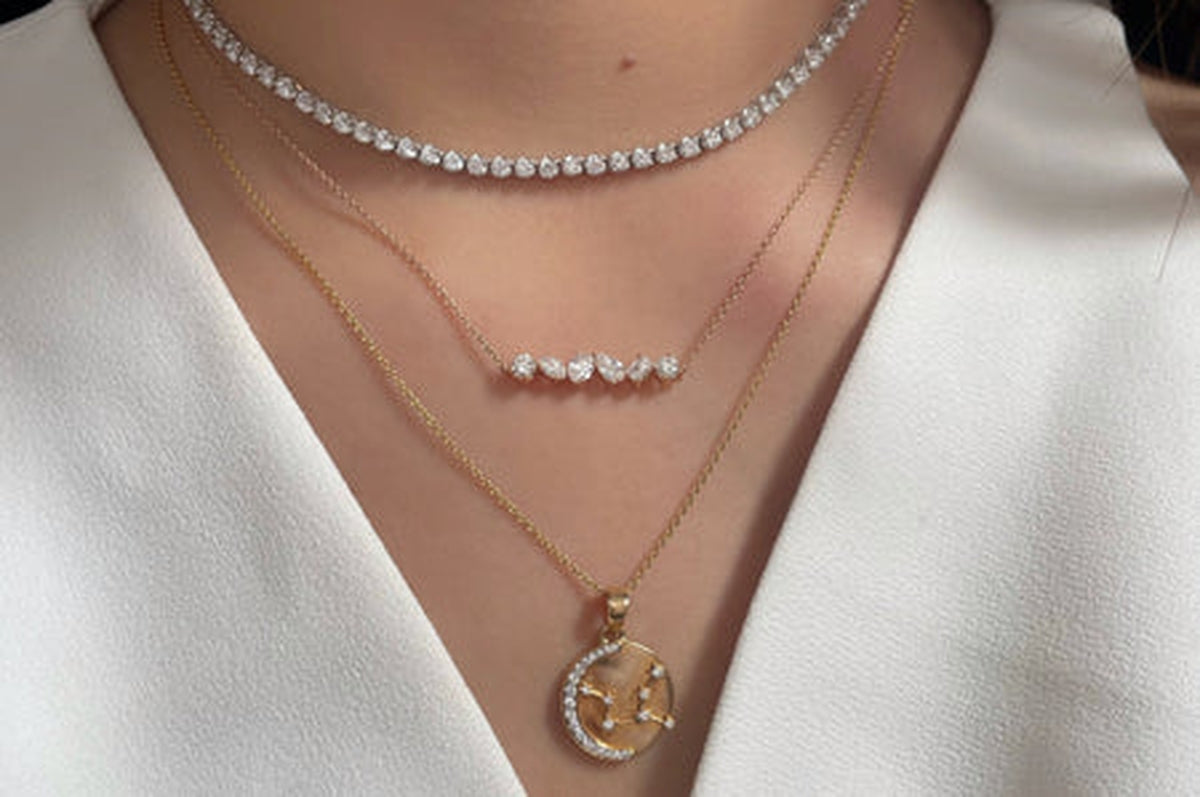 Here's a caption: three necklaces adorned on a neck.