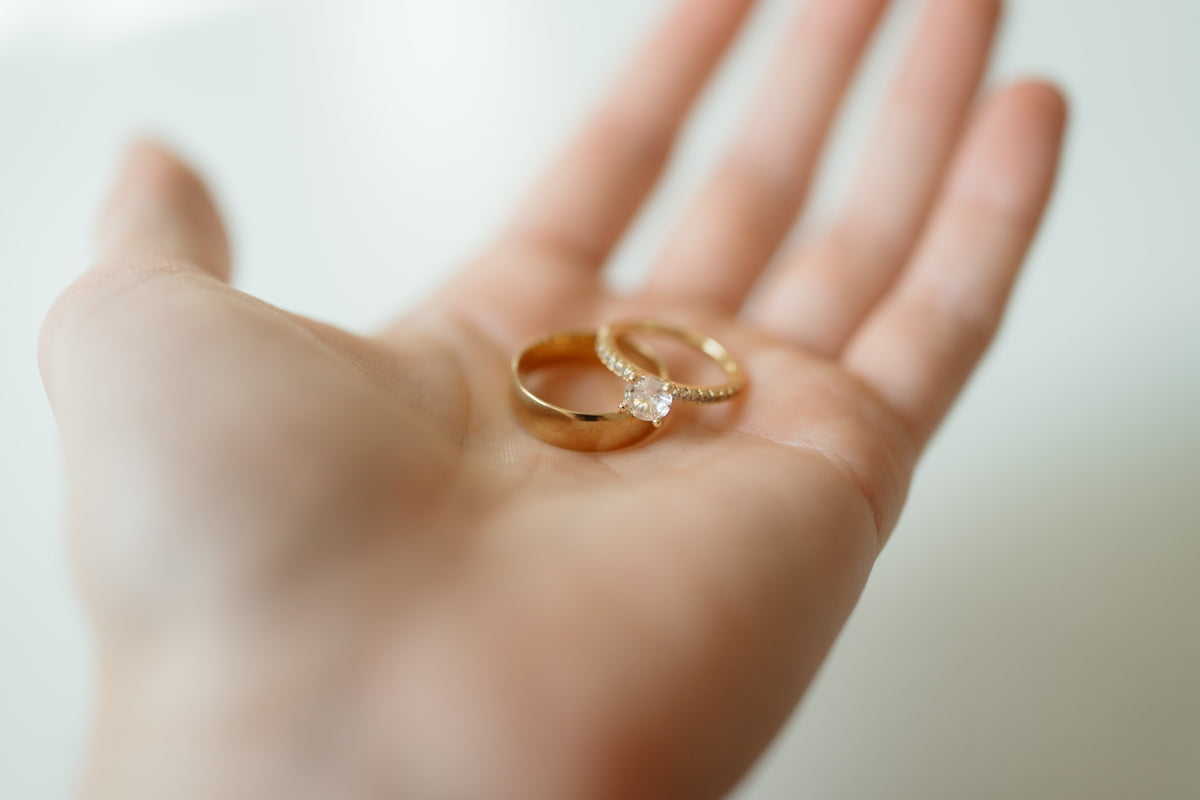 Zwei goldene Ringe ruhen auf einer Hand.